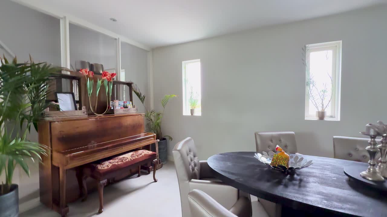 Camera pulls back revealing a bright modern room with wooden piano and dining table