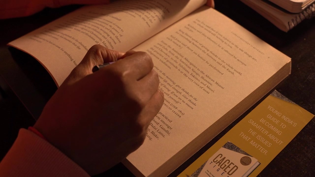 Close-up of a person reading an inspirational book in warm indoor light.