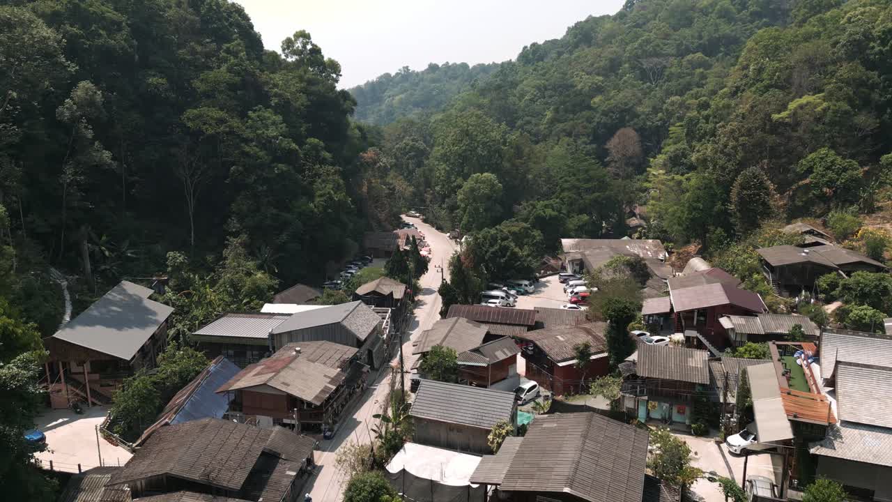 Vista aérea de drone da vila de Mae Kampong em Chiang Mai coberta por poluição atmosférica durante a estação de queimadas, destacando a poluição do ar em uma paisagem montanhosa cênica.