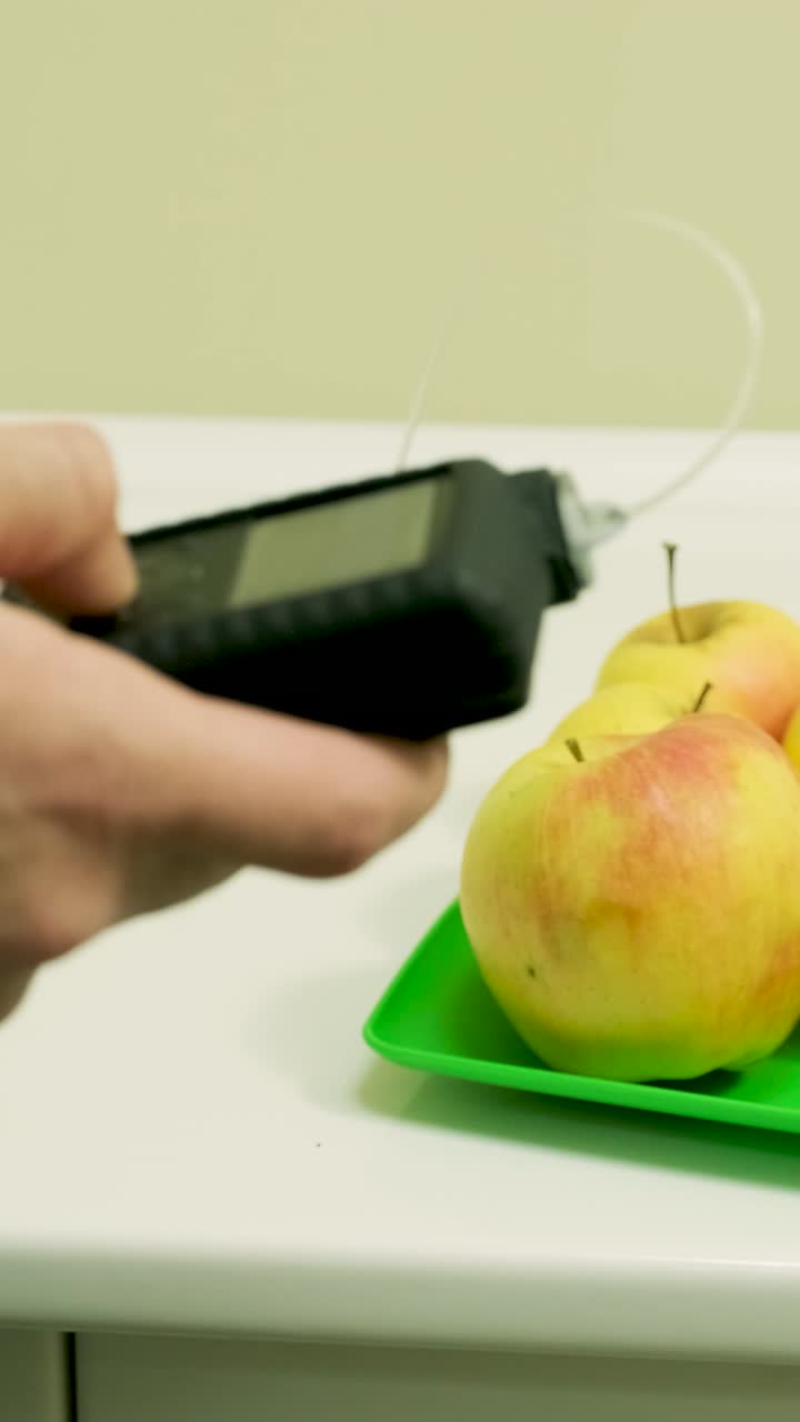 Person's Hand Operating Insulin Pump Near Fresh Apples