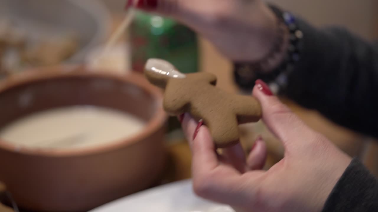Close-up shot of a lady putting icing on a gingerbread man