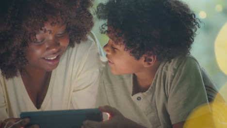 joyous african american mother and son using tablet in evening