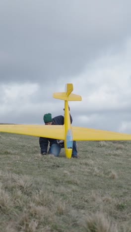 a person with a yellow glider on a grassy hill