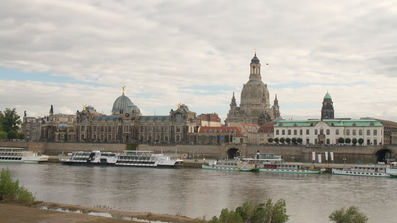 Dresden skyline along the Elbe River stunning panorama view of the Frauenkirche and historic architecture. Boats glide on the water a cloudy sky