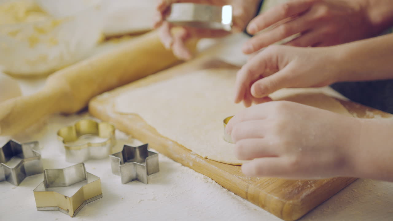 Close up of the Caucasian woman's and child's hands making forms from the daugh on the kitchen table. Indoors