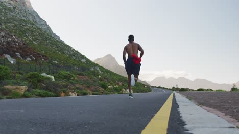 hombre afroamericano haciendo ejercicio al aire libre corriendo en una carretera costera