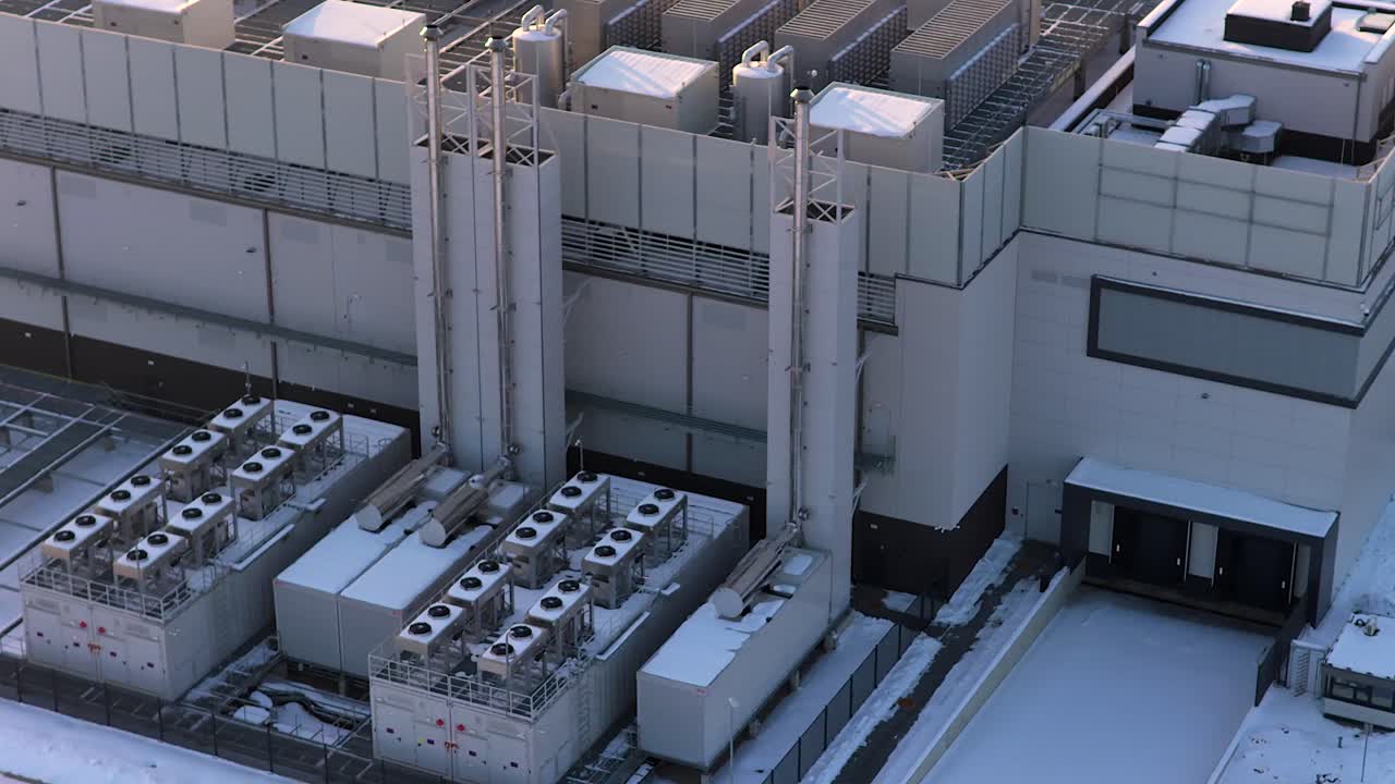 Drone orbiting an advanced data center with powerful cooling systems and hvac units on the exterior, covered in snow during a cold winter day