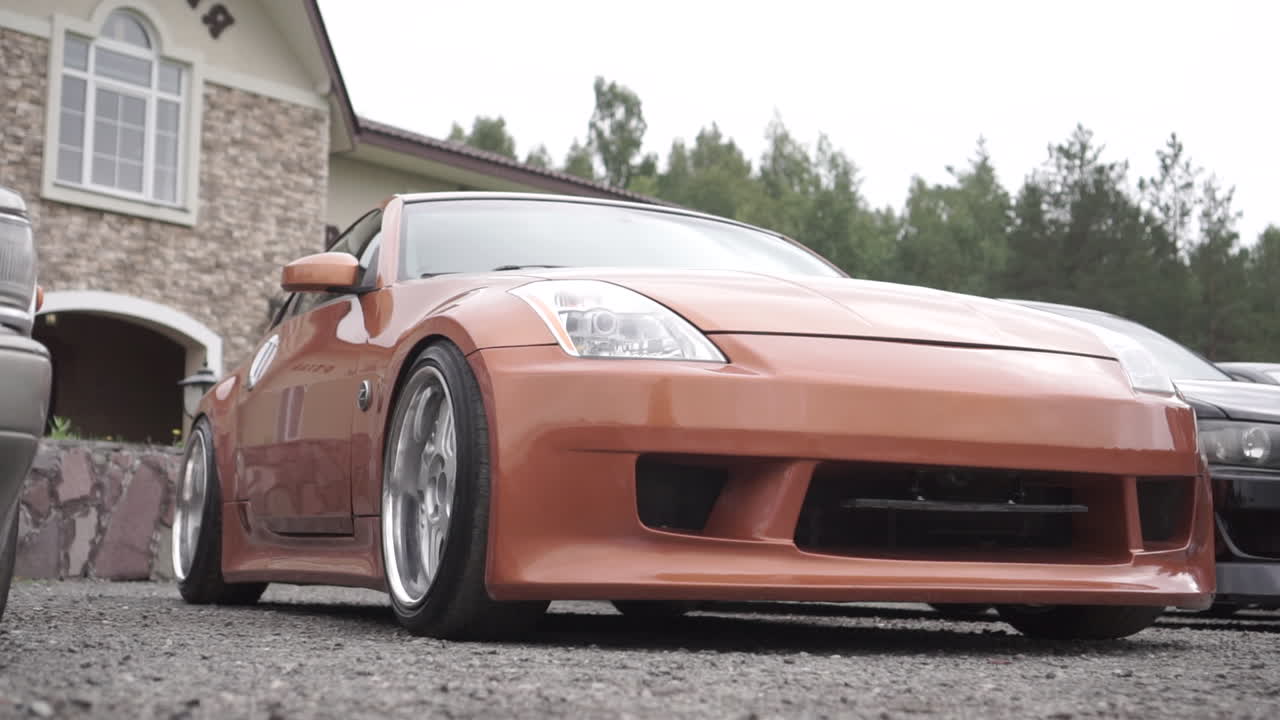 Person standing in front of an orange sports car