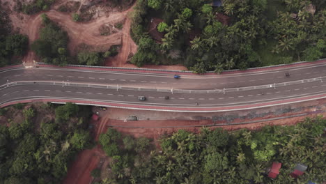 una carretera de cuatro carriles bien construida a través de una zona rural en la india. vista aérea de seguimiento de un coche que sube por una carretera de asfalto en un día nublado. una fotografía aérea de un automóvil que conduce en una autopista vacía en la india rural.