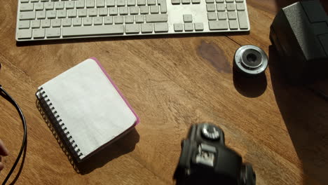 la mano toma la cámara dslr y el bloc de notas del escritorio de la computadora a la luz de la mañana