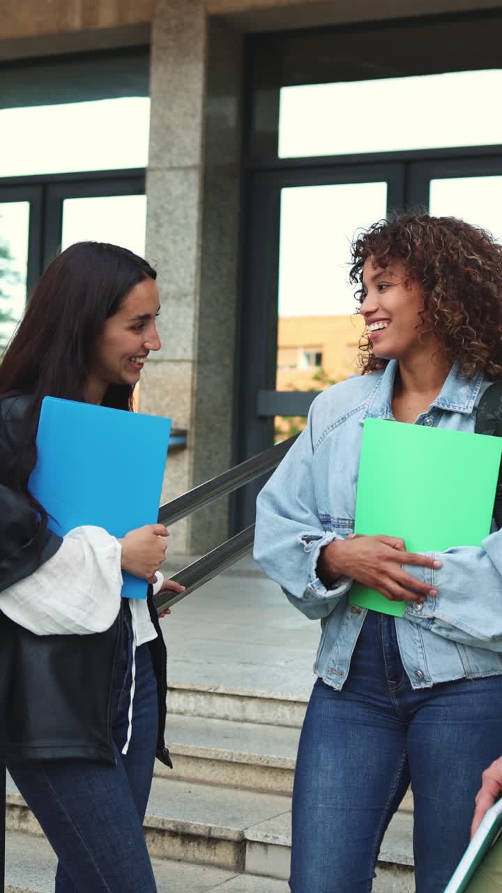 Due giovani studentesse che parlano e sorridono fuori dall'edificio universitario