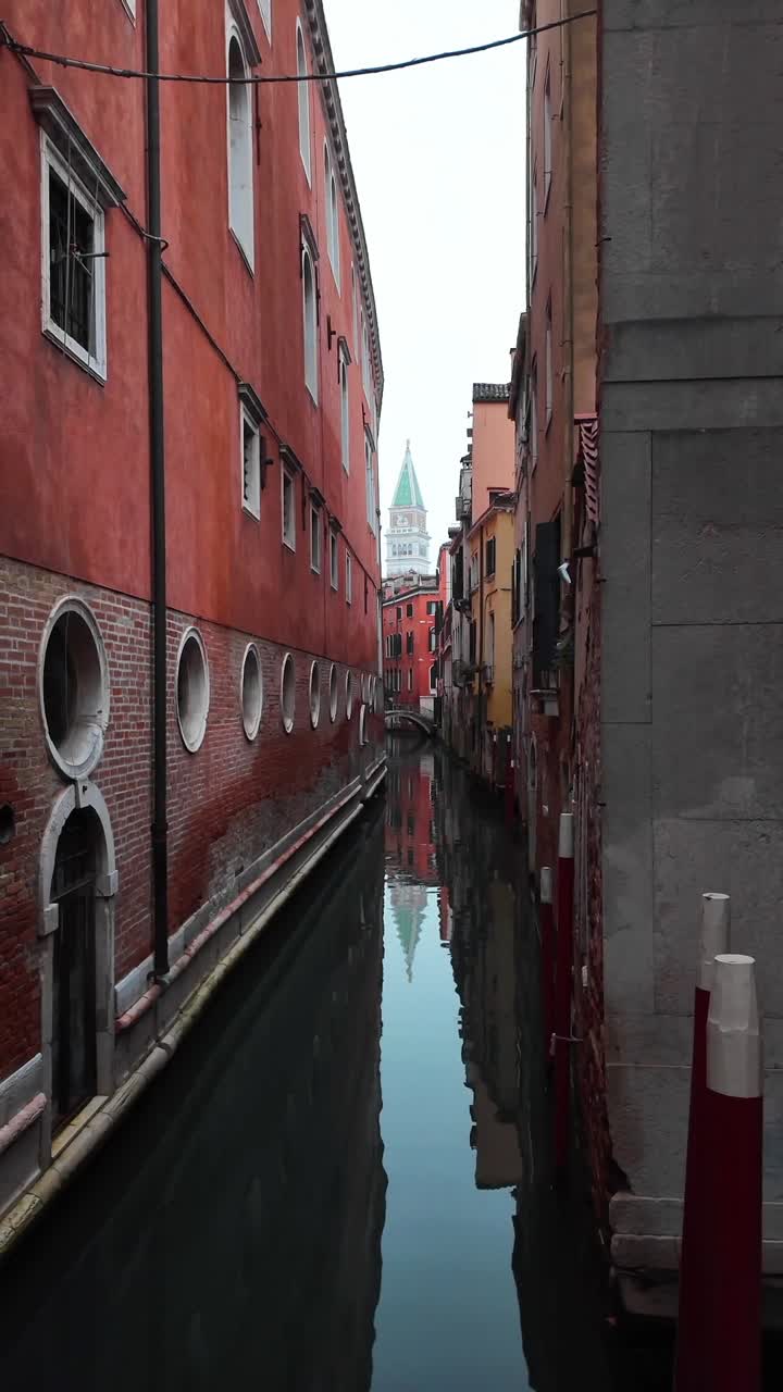 Narrow canal Venice with buildings lining both sides St. Mark's Campanile bell tower