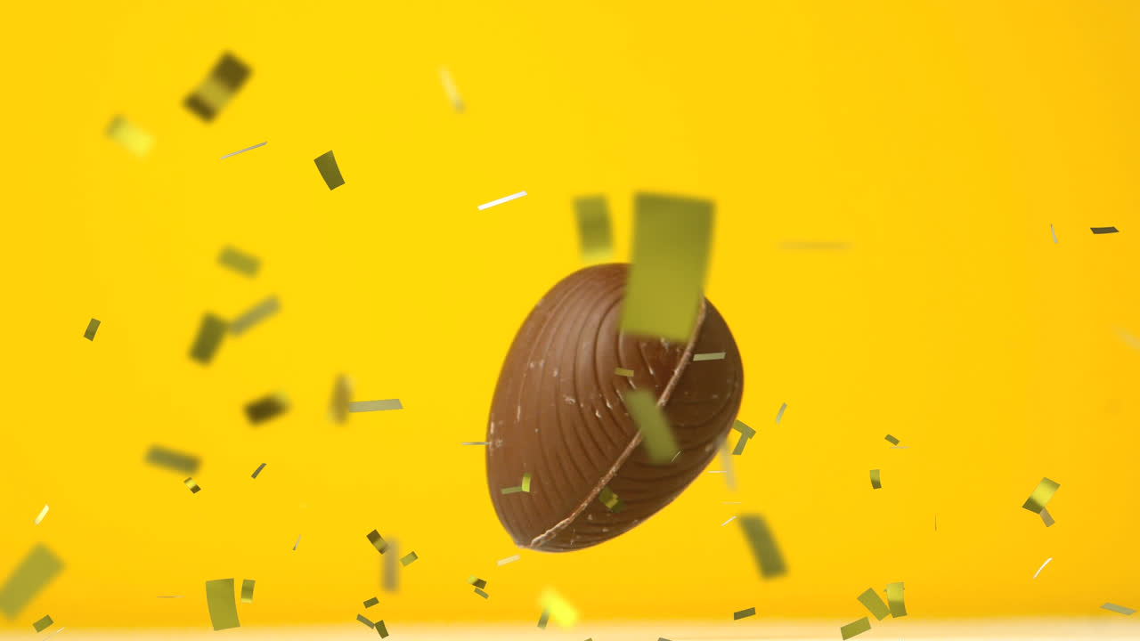 Animation af guldkonfetti og chokolade påskeæg, der falder og hopper på gul baggrund