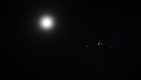 chorros de avión por la luna llena en una noche oscura