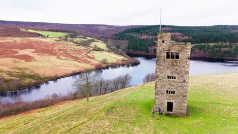 old derelict castle, monument, disused stone tower, with people walking around and flying a drone