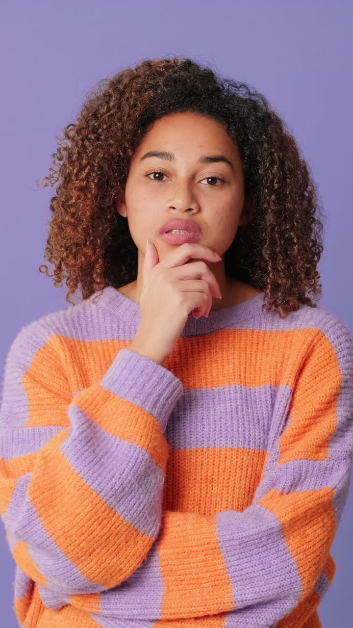 Young Woman Pondering and Smiling on Purple Background