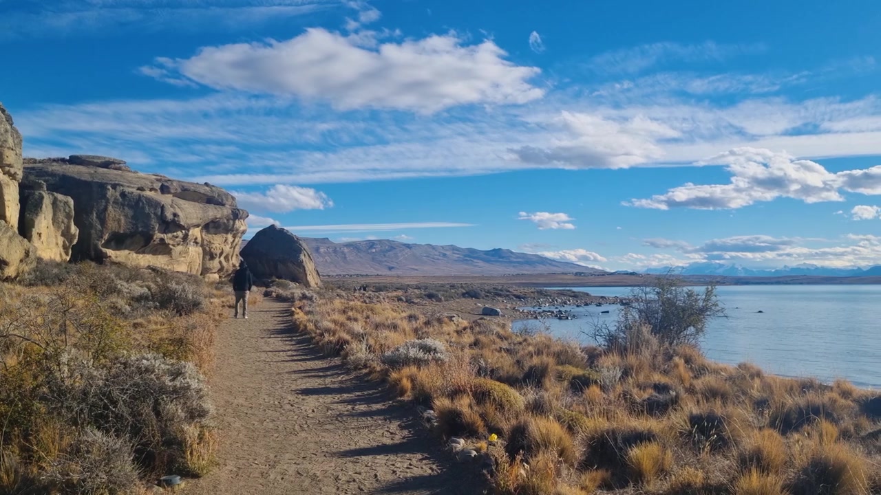 Splendido paesaggio patagonico con un uomo che cammina lungo il Lago Argentino glaciale a Punta Walichu vicino a El Calafate, Argentina, natura selvaggia suggestiva, luce serale dorata e natura incontaminata.