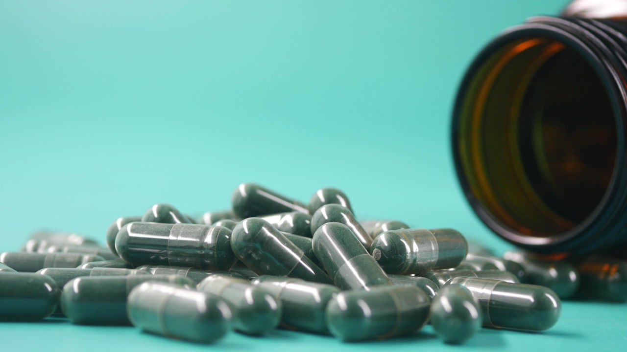 Close Up of Green Pills Spilled from a Medicine Bottle