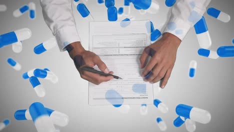 Animation-of-hands-holding-a-pen-with-a-sheet-of-paperover-pills-falling-down-in-the-background.-