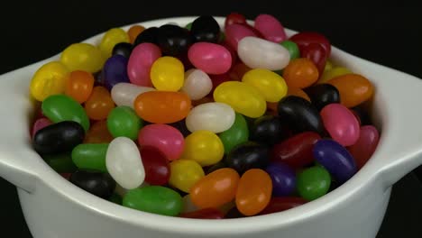 delicious colorful snack: sugary jelly bellies in white bowl rotating