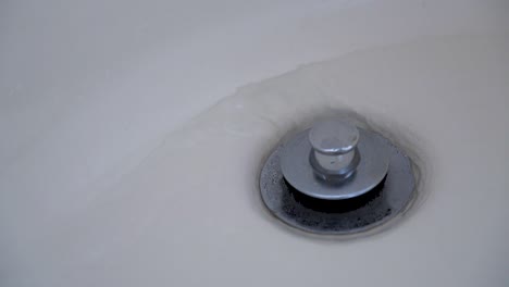 water runs into a bathtub drain.