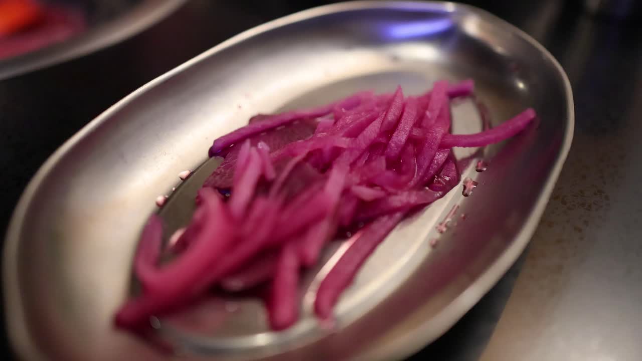 palillos para comer recogiendo cebollas rojas encurtidas del plato