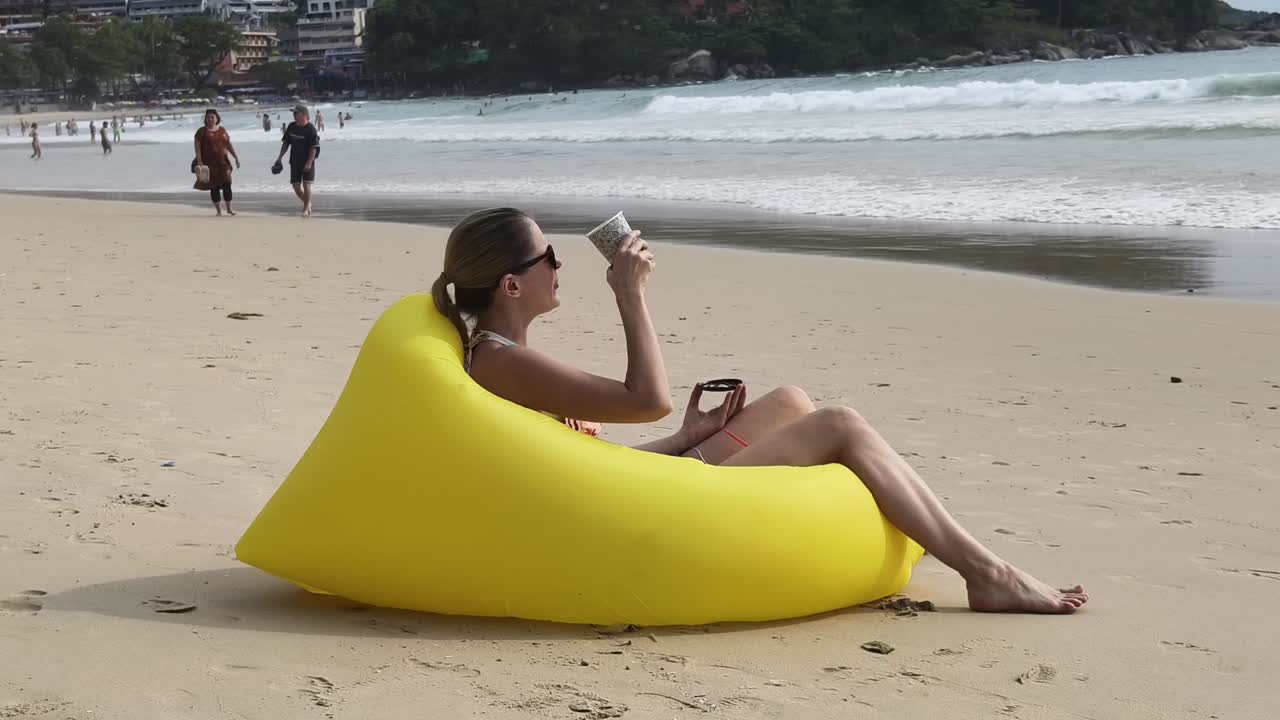 mujer disfrutando de café en una silla inflable de playa