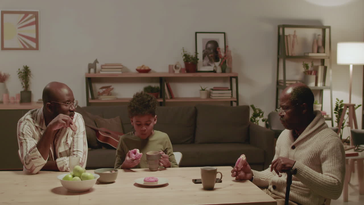 흑인 남자와 소년이 집에서 과자를 먹고 있다