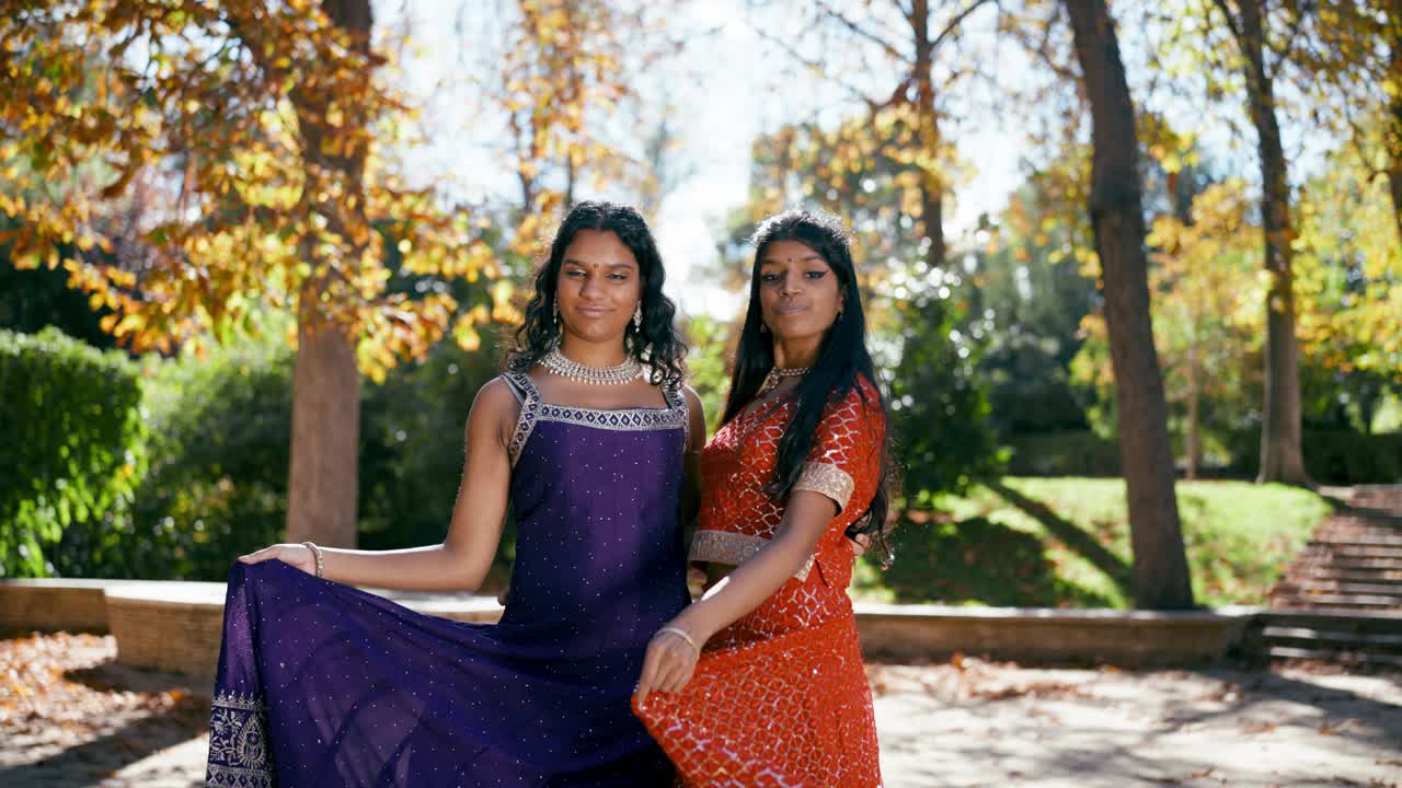 Duas mulheres ao ar livre vestindo trajes tradicionais indianos