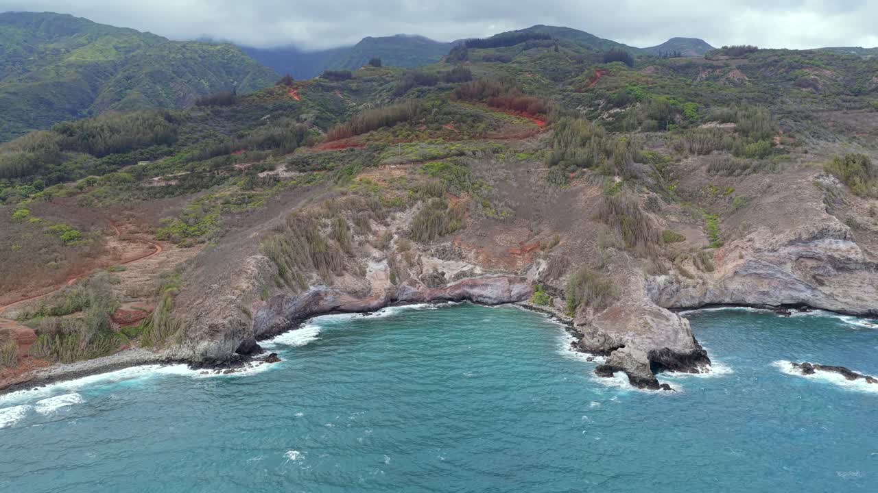 Drone pans across a rocky Hawaiian shore rarely seen by visitors, revealing epic cliff faces and turning to show the magnificent view of the island from the sea. 4 of sequence of 5