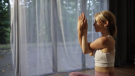 concentrated young blonde woman doing yoga stretching at home concentrated young blonde woman doing yoga stretching at home morning yoga at home in a room with a modern interior