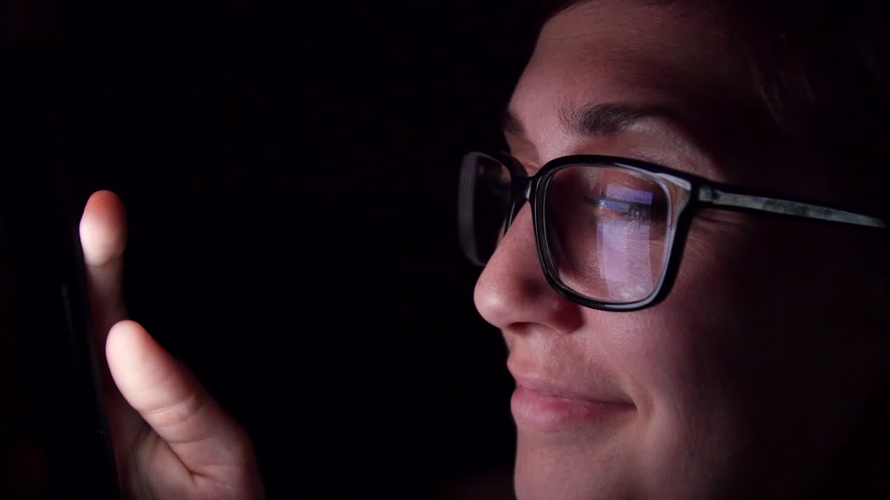 mujer sonriente se desplaza a través de las redes sociales a altas horas de la noche