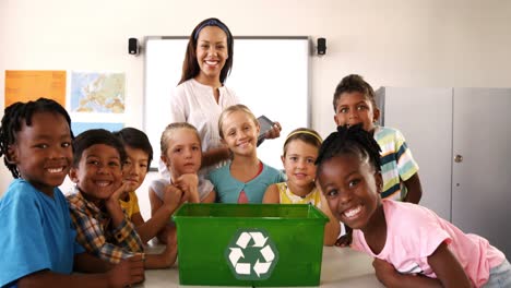 school kids putting waste bottles in recycle bin in classroom