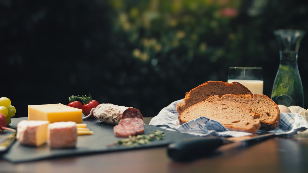 A spread of salami, cheese, and bread on a garden table. A visual treat for foodies and social media food influencers. Great for food vlogs, recipe videos, and appetizing product presentations