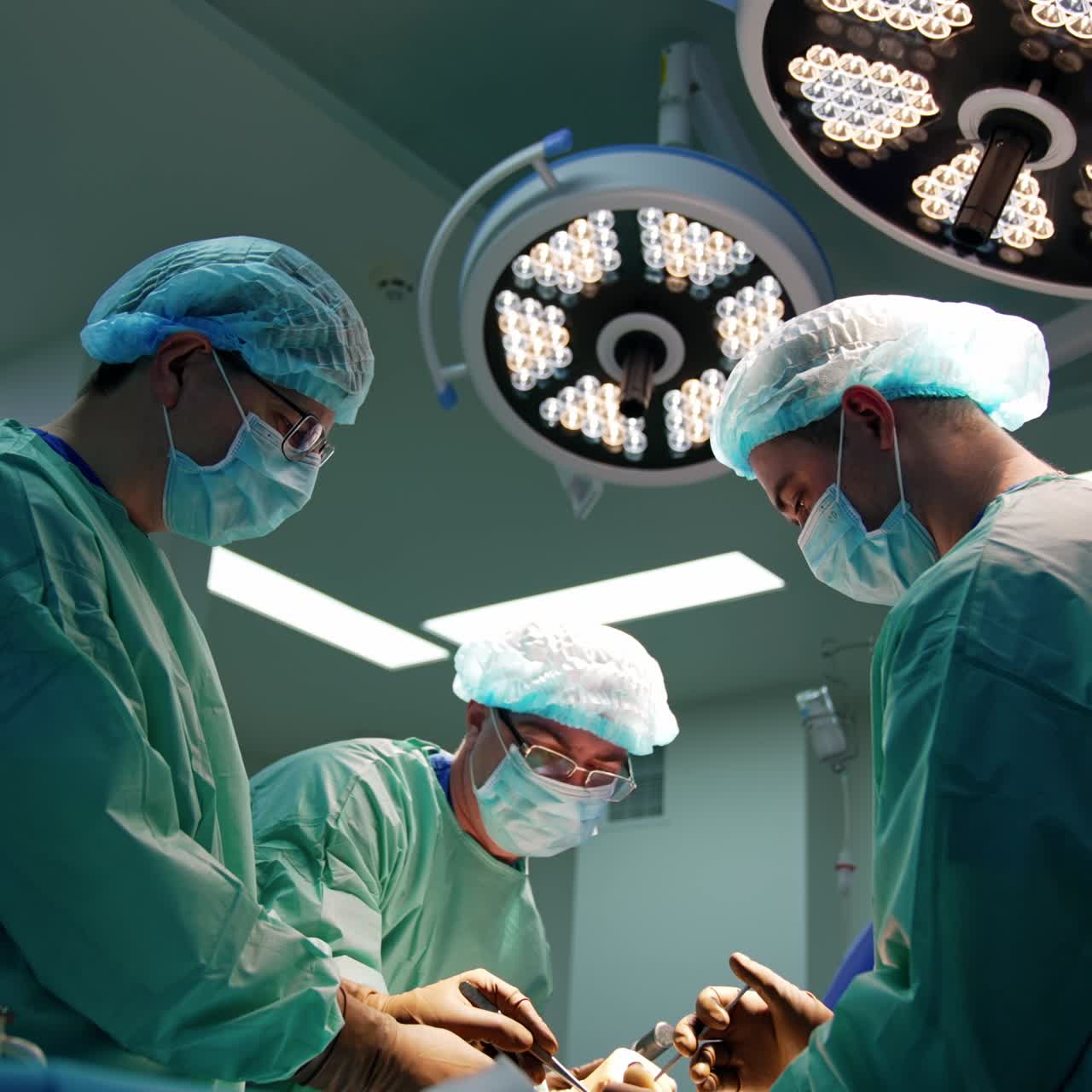 Surgical team uses a range of metal orthopedic tools in operation. Three doctors perform surgery in modern hospital
