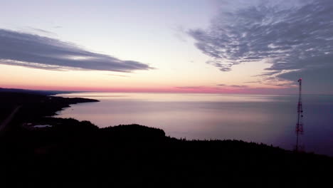 Aerial-shot-of-a-telecommunication-radio-tower-at-sunrise-on-Lake-Superior