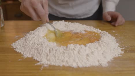 chef mezclando yemas de huevo con la masa de pasta con tenedor