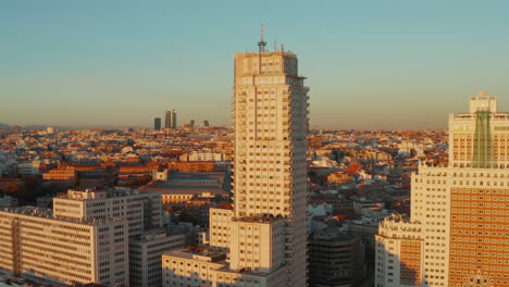 Forwards-rising-footage-of-old-high-rise-buildings-at-Spain-square-with-cityscape-in-background-at-sunset-time.