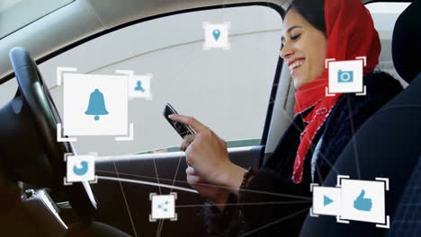 una red de iconos de conexiones contra una mujer con hijab que usa un teléfono inteligente en el coche