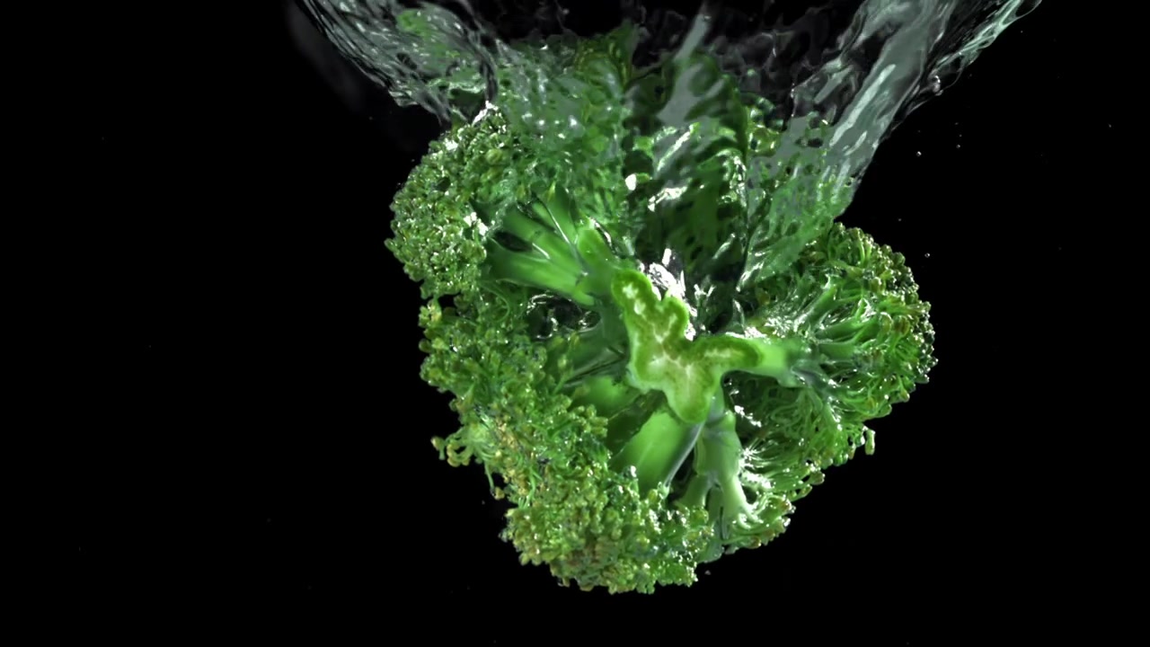 Broccolo verde fresco che cade nell'acqua al rallentatore