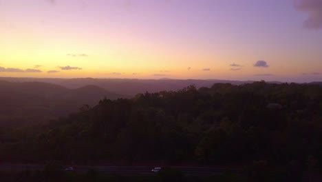 Aerial-view-of-tropical-forest-valley-road-in-Kondalilla,-Australia-during-sunset