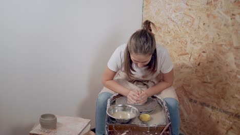mujer moldeando arcilla en una rueda de cerámica