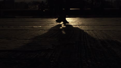 shadow of a person walking across a street or sidewalk at night with a light reflecting off the pavement - slow motion