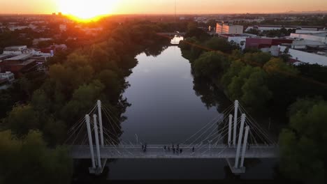 Vista-Aérea-Sobre-Un-Puente-En-Culiacán,-Puesta-Del-Sol-En-México---Reversa,-Disparo-De-Drones