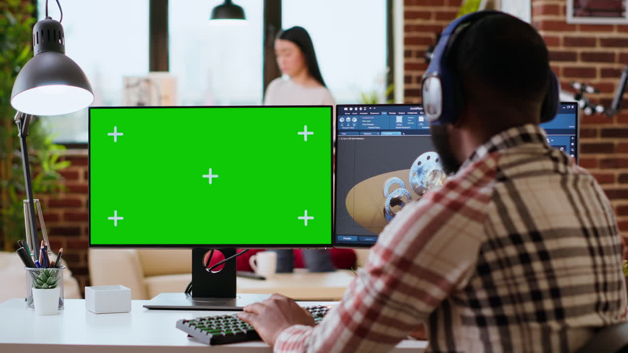Male freelance designer works remotely on 3D prototypes using green screen