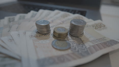 polish zloty bills and stacked coins on top of laptop computer