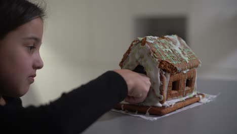 niña linda con pan de jengibre casa espeluznante con glaseado festivo y galleta en forma de fantasma. feliz halloween