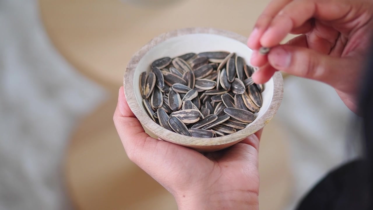 Personne tenant un petit bol en bois de graines de tournesol