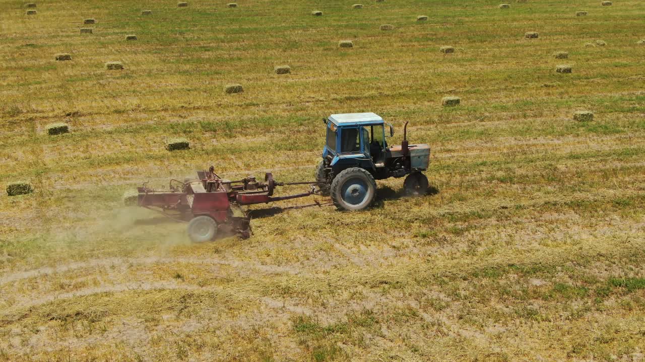 tractor de empacado cortando tallos de plantas de cáñamo para formar pacas cuadradas en las tierras de cultivo