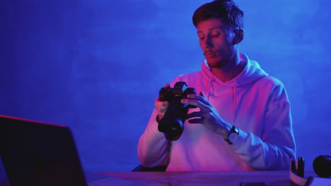 Man-working-with-a-computer-and-a-professional-photo-camera-on-a-colorful-background